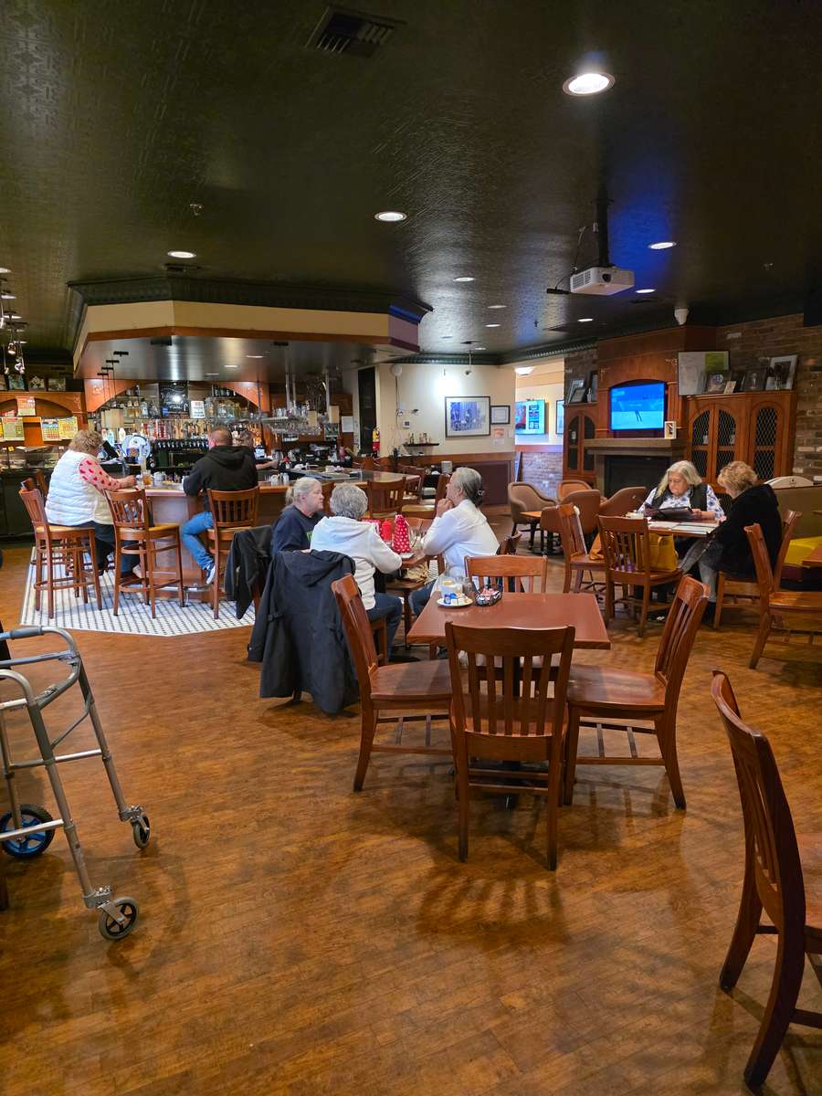 A wide view of the main lounge bar at Collector's Choice Restaurant in Snohomish, showing the bar counter, wooden barstools, and multiple TV screens for sports.