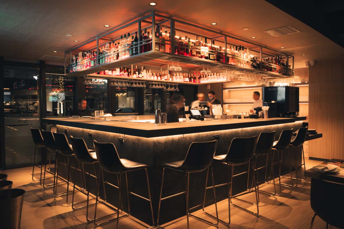 Interior bar area with warm lighting and elevated seating around a bar table