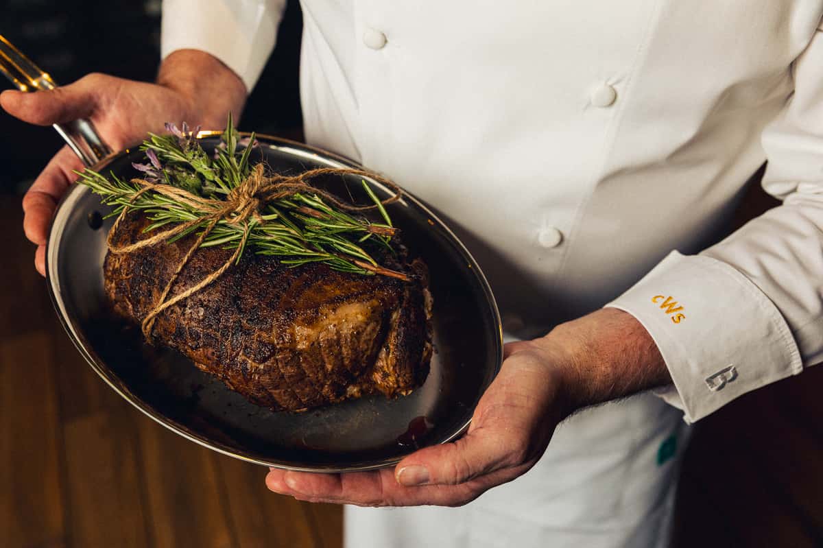 Chef Holing a perfectly cooked leg of lamb