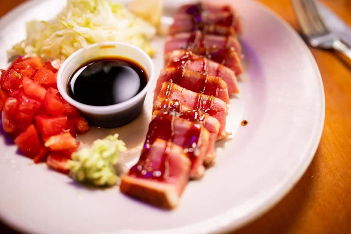 Seared ahi tuna drizzled with sauce, served with diced tomatoes, shredded lettuce, wasabi, and a soy dipping sauce.