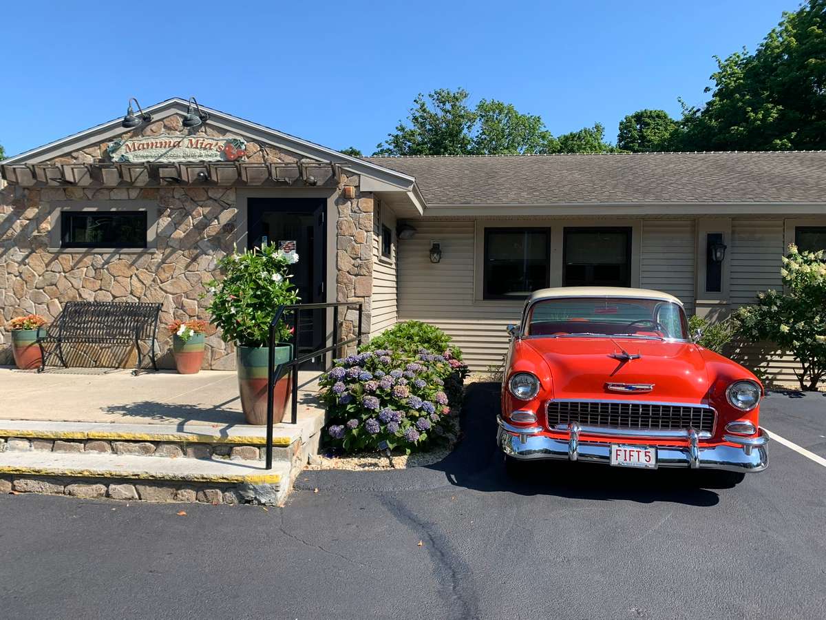 1955 orange cadillac in front of stone facade of restaurant