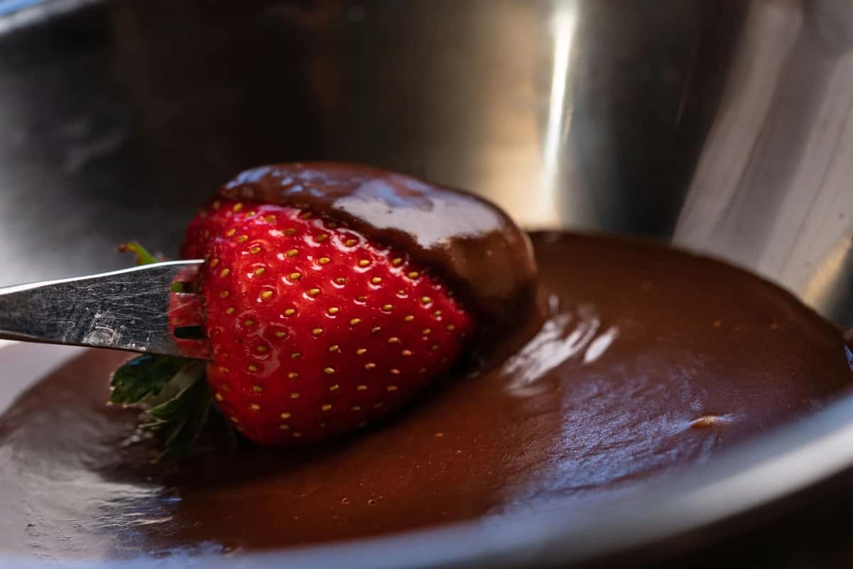 Strawberry being dipped into chocolate fondue