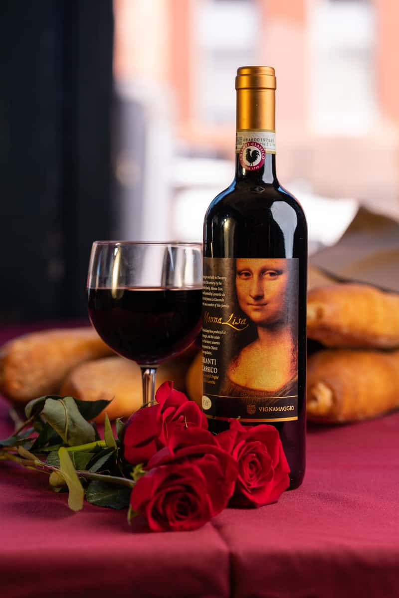 Wine glass filled with red wine beside a bottle of wine