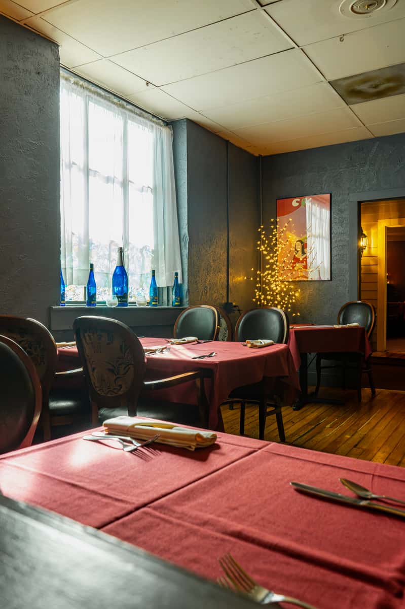 Dining room with tables decorated with red tablecloths and bright windows