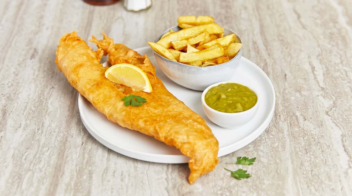 Traditional battered fish served with golden chips, mushy peas and a fresh lemon wedge.