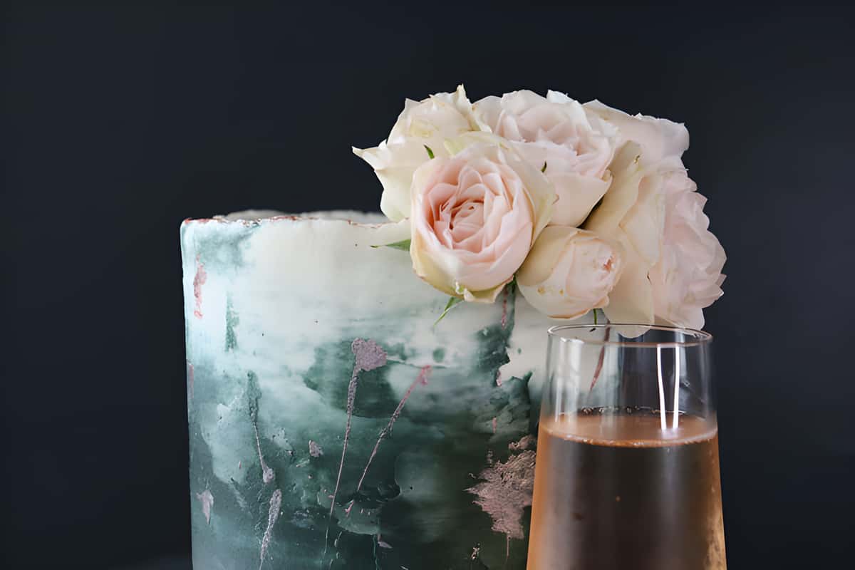 marble frosted cake topped with roses with glass of champagne