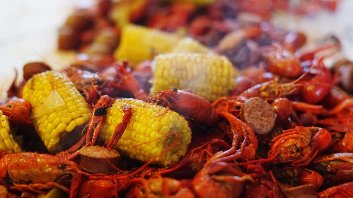 Seafood boil with crawfish, corn, and sausage in a seasoned sauce.