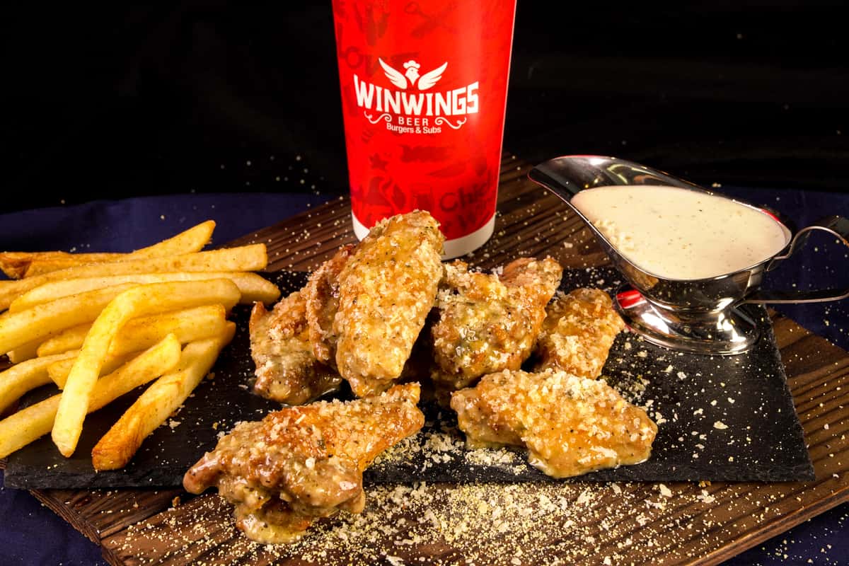 Chicken Wings sprinkled with a drink and a side of fries