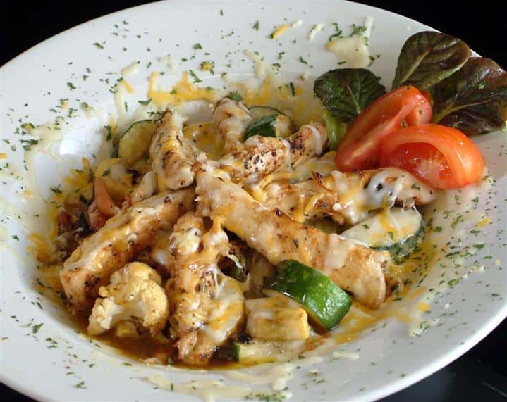 Chicken with zucchini, tomatoes, and melted cheese.