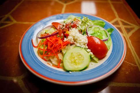 salad in a bowl topped with cucumbers, tomatoes, shredded carrots