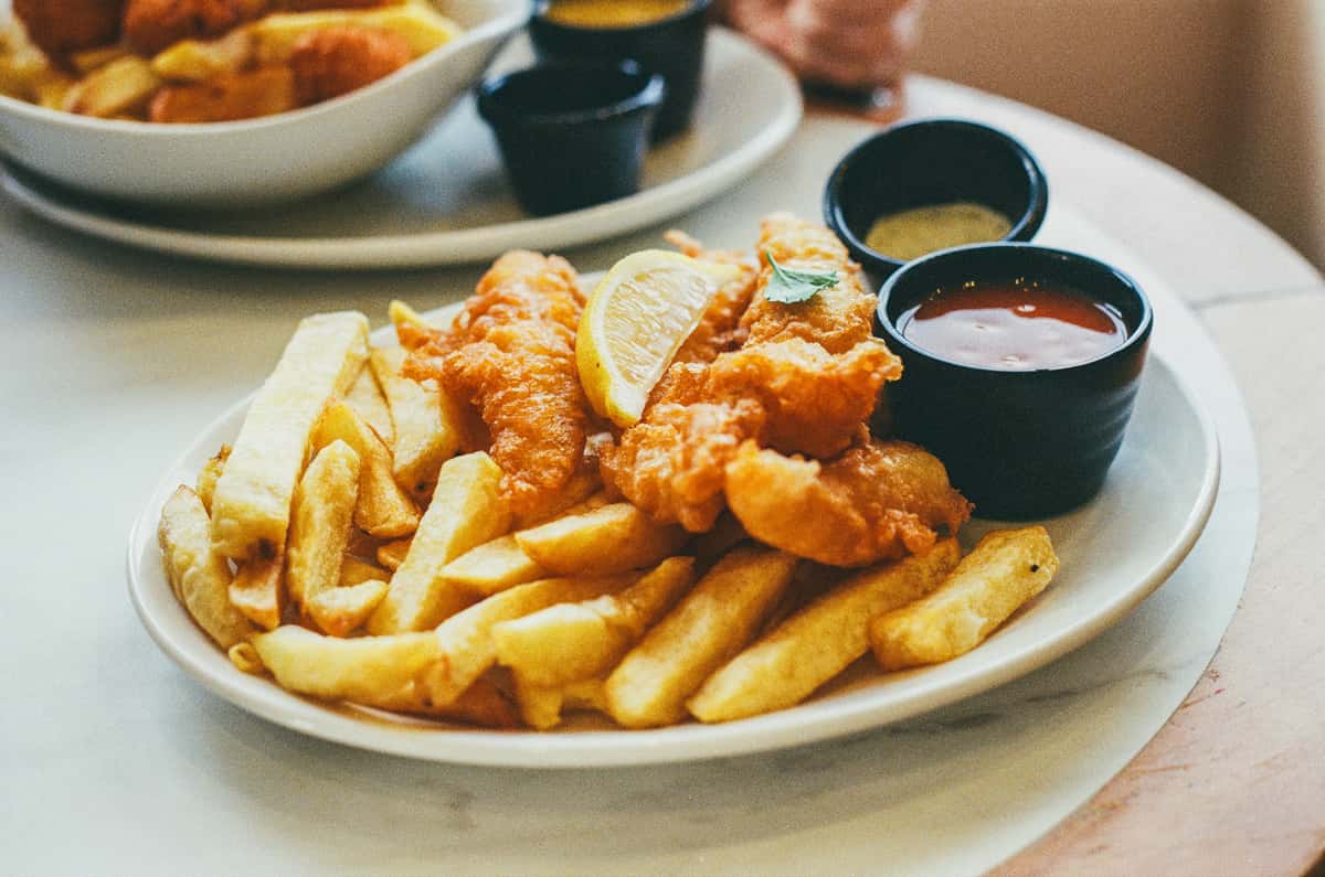 Crispy battered fish and chips served with chips, a lemon wedge and dipping sauces at Fisherman's Dock, Greenock