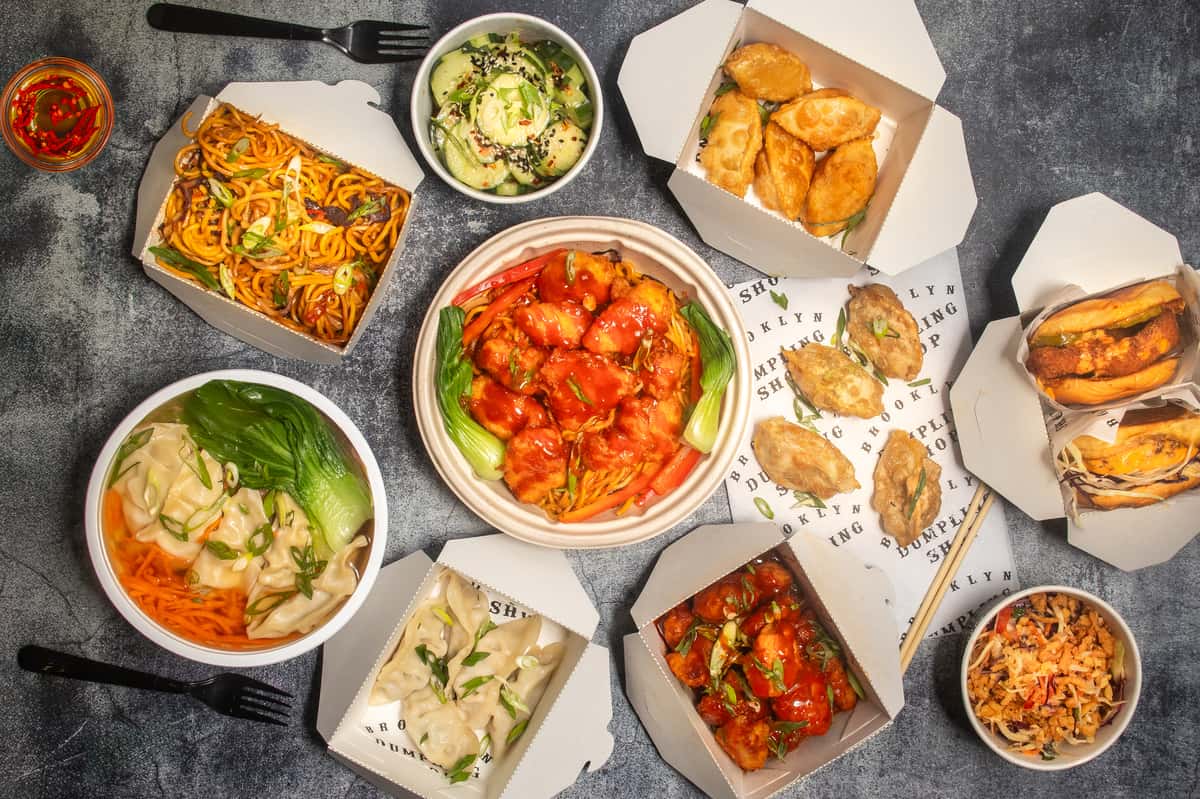 Overhead shot of food boxes with dumplings, noodles and sides
