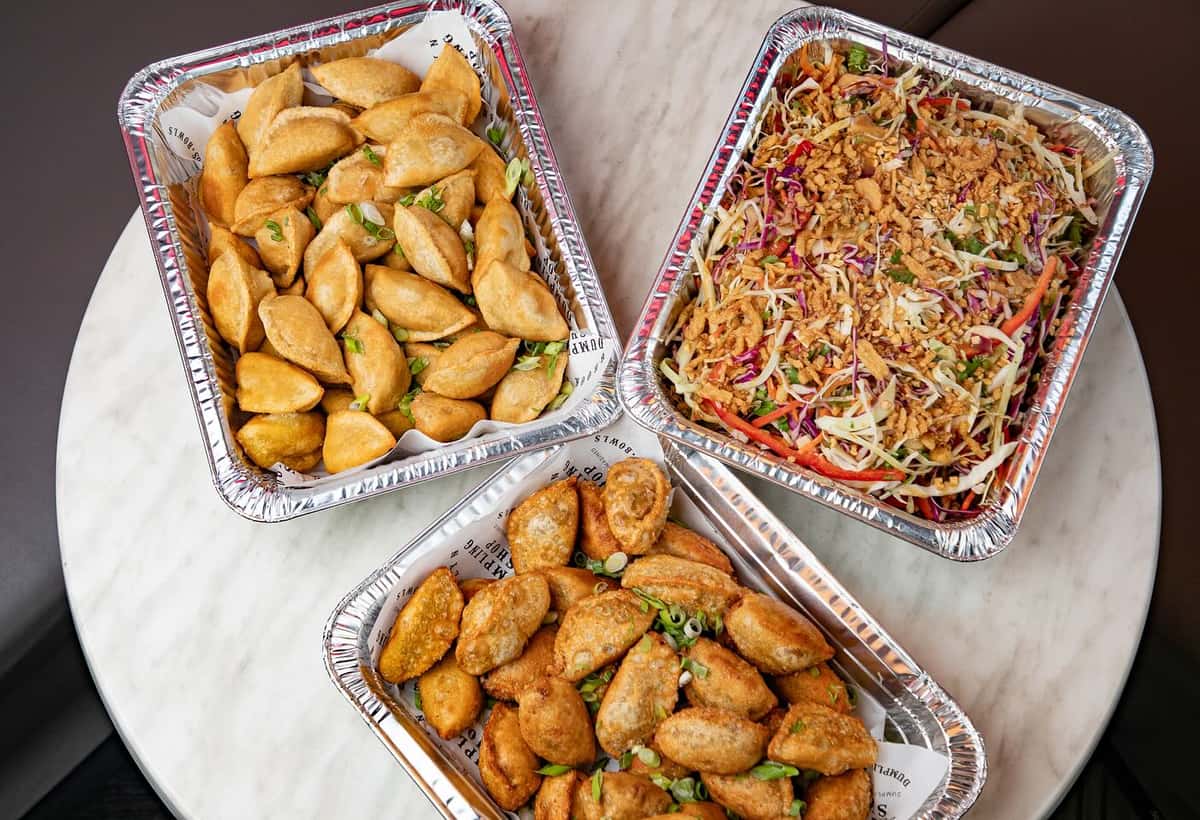 Three pans of catered dumplings and noodles