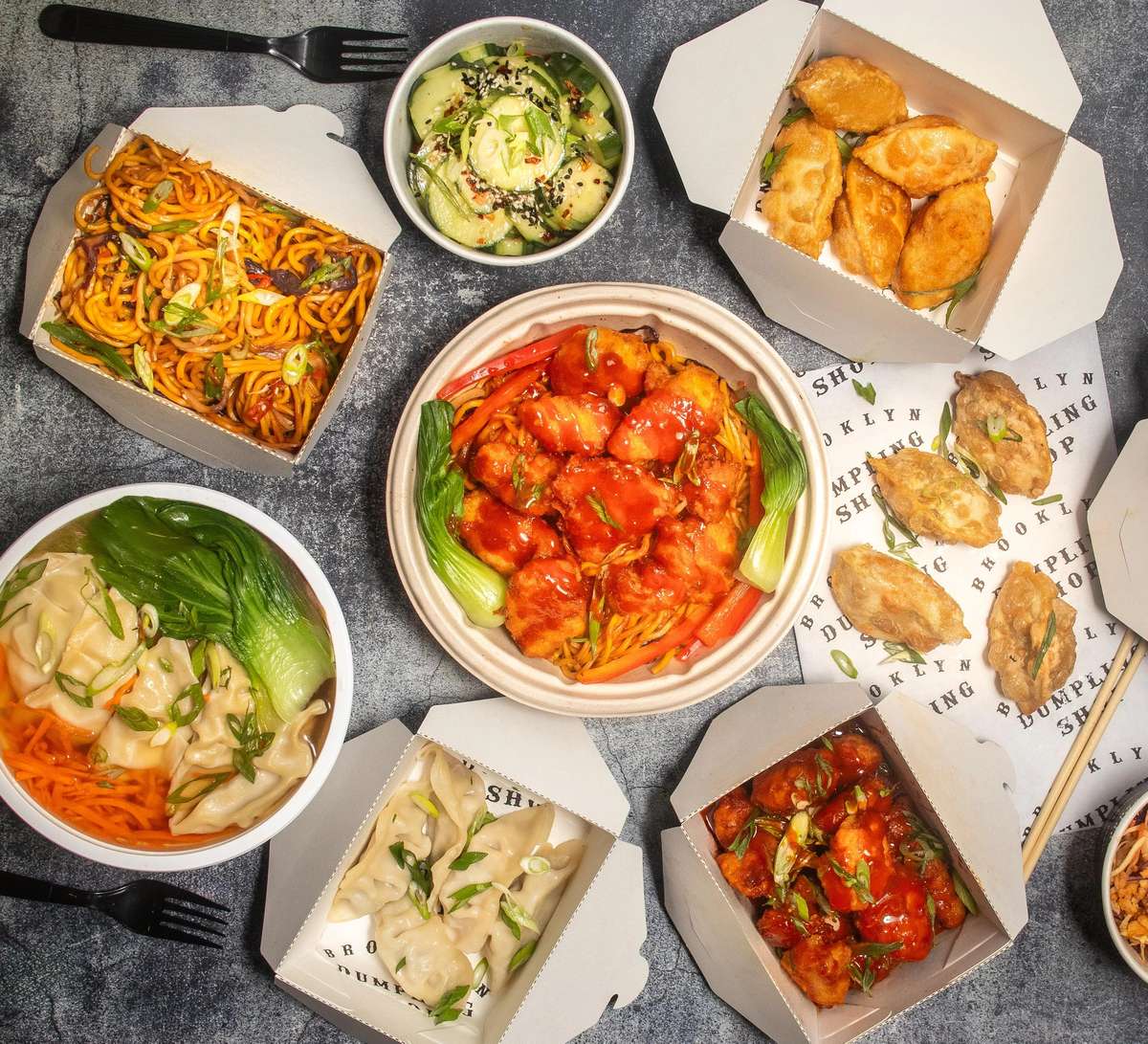 Overhead shot of food boxes with dumplings, noodles and sides