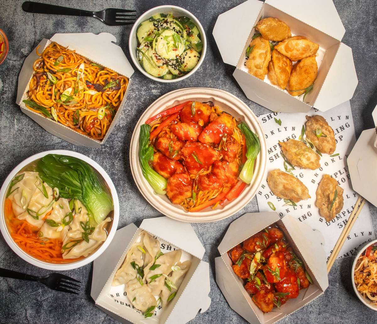 Overhead shot of food boxes with dumplings, noodles and sides