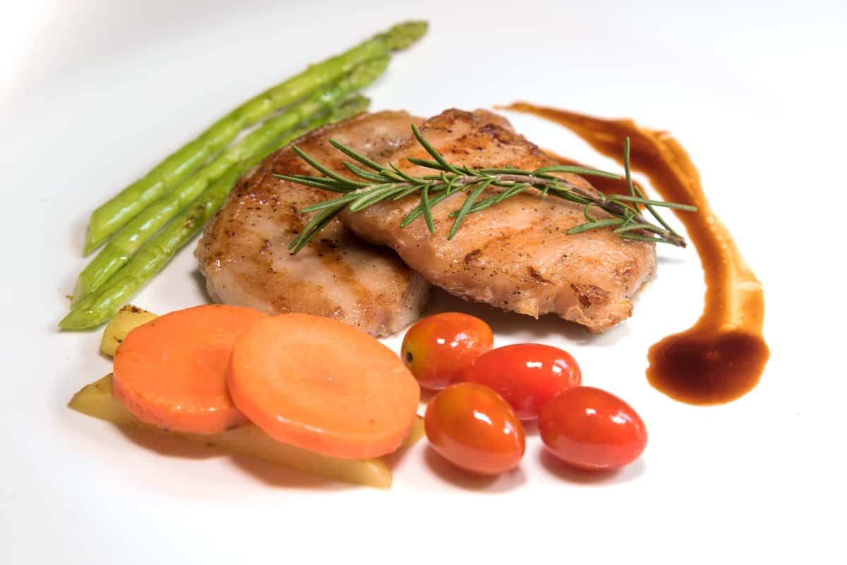 Meat dish served with a slide of vegetables and a sauce