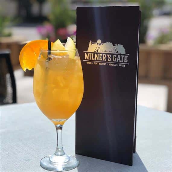 Milner's Gate menu standing next to a glass of sangria with orange and lemon slices