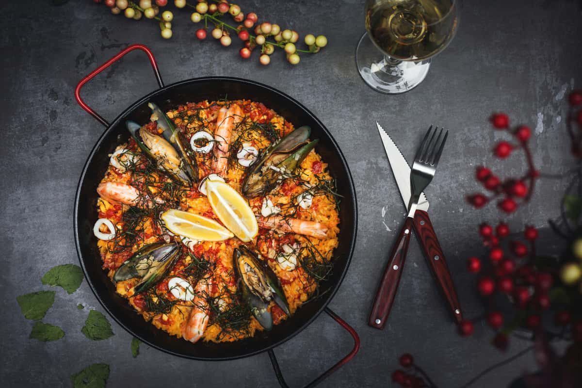 Authentic Spanish seafood paella with saffron rice, mussels, shrimp, calamari, and lemon wedges, served in a traditional black paella pan.
