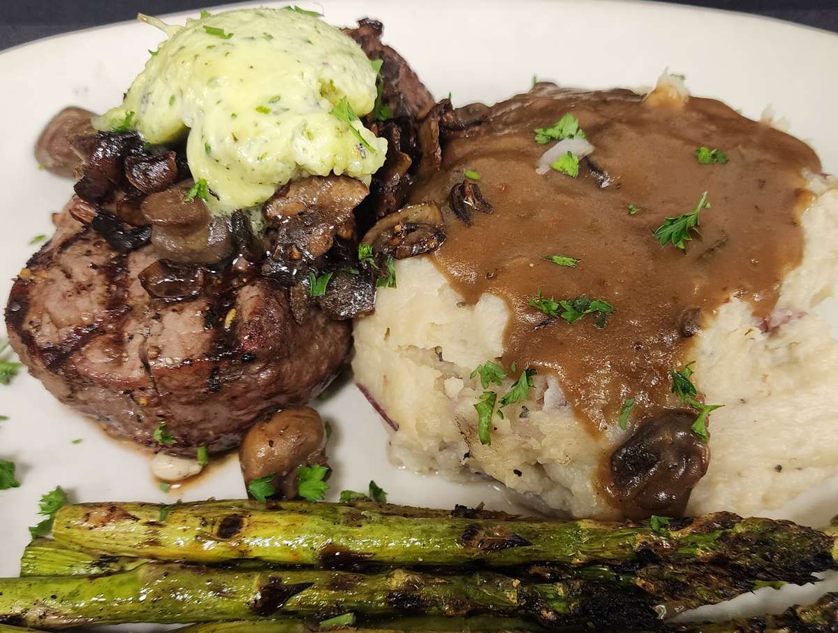 Filet Mignon, mashed potatoes covered in brown gravy, and asparagus spears