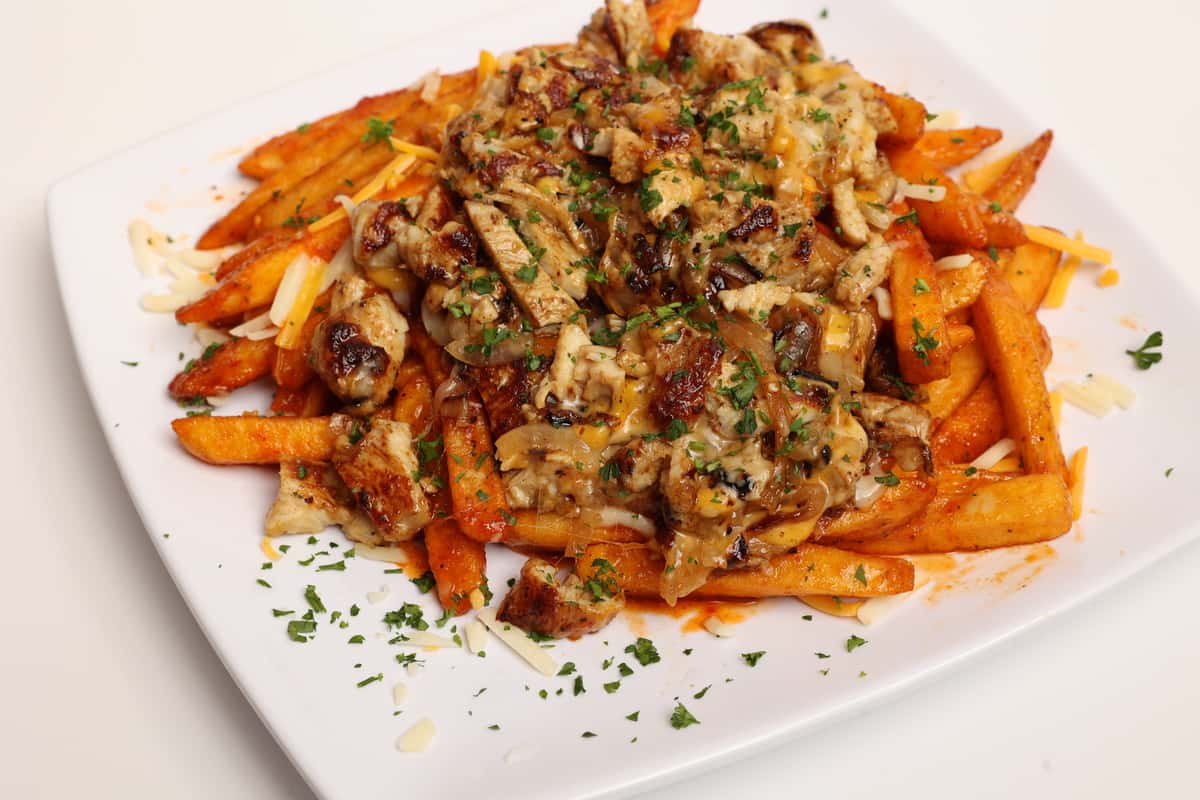 Square plate of fries topped with chicken and cheese, likely for a menu or catering service. This image represents a food offering on a restaurant's website gallery page.