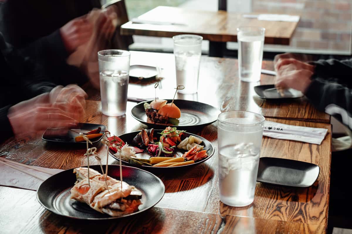 Assorted Japanese small plates served on a wooden table with people dining