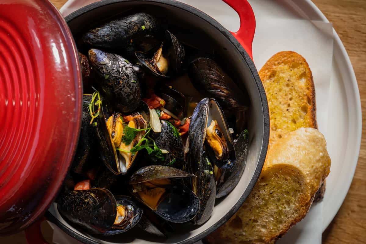 Mussels in a red clay pot with toasted bread