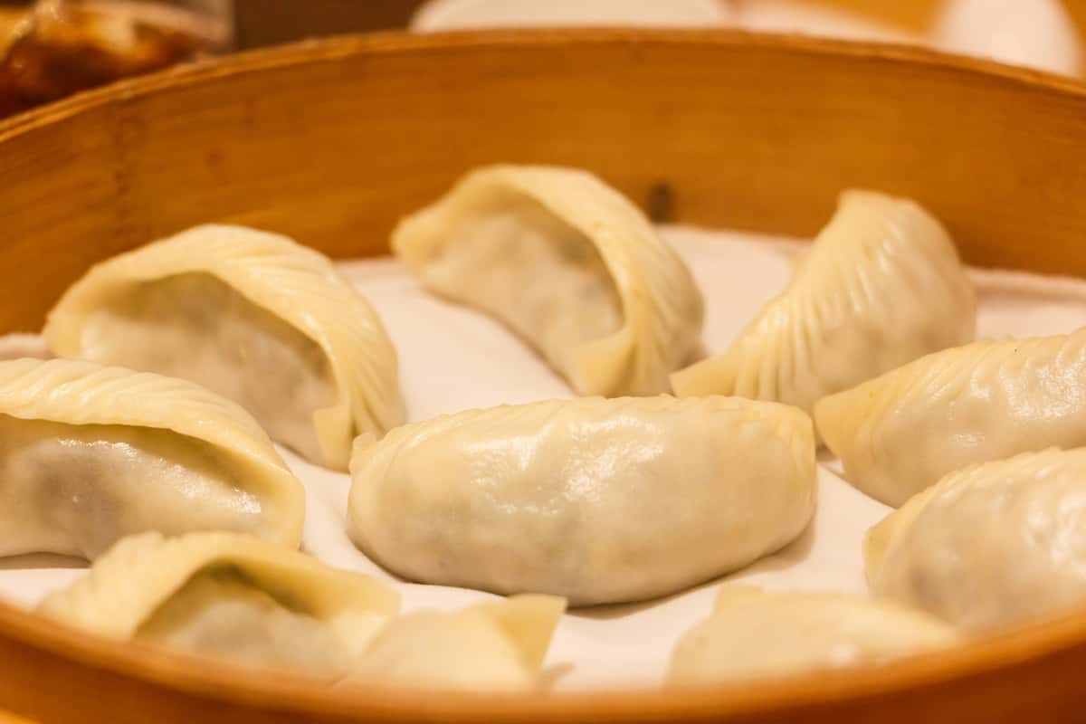 Steamed dumplings arranged in a bamboo steamer basket lined with parchment paper.