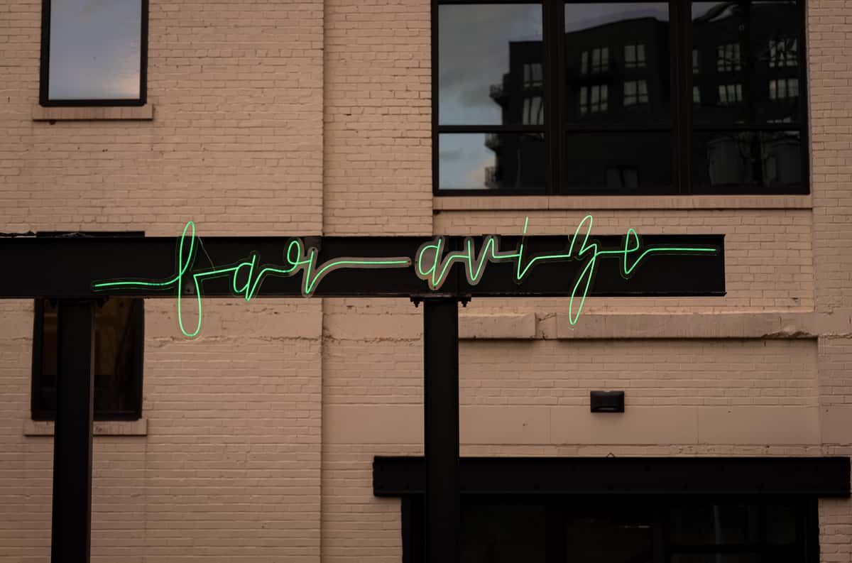 A neon sign reading "far avize" mounted on a white brick wall of a building.