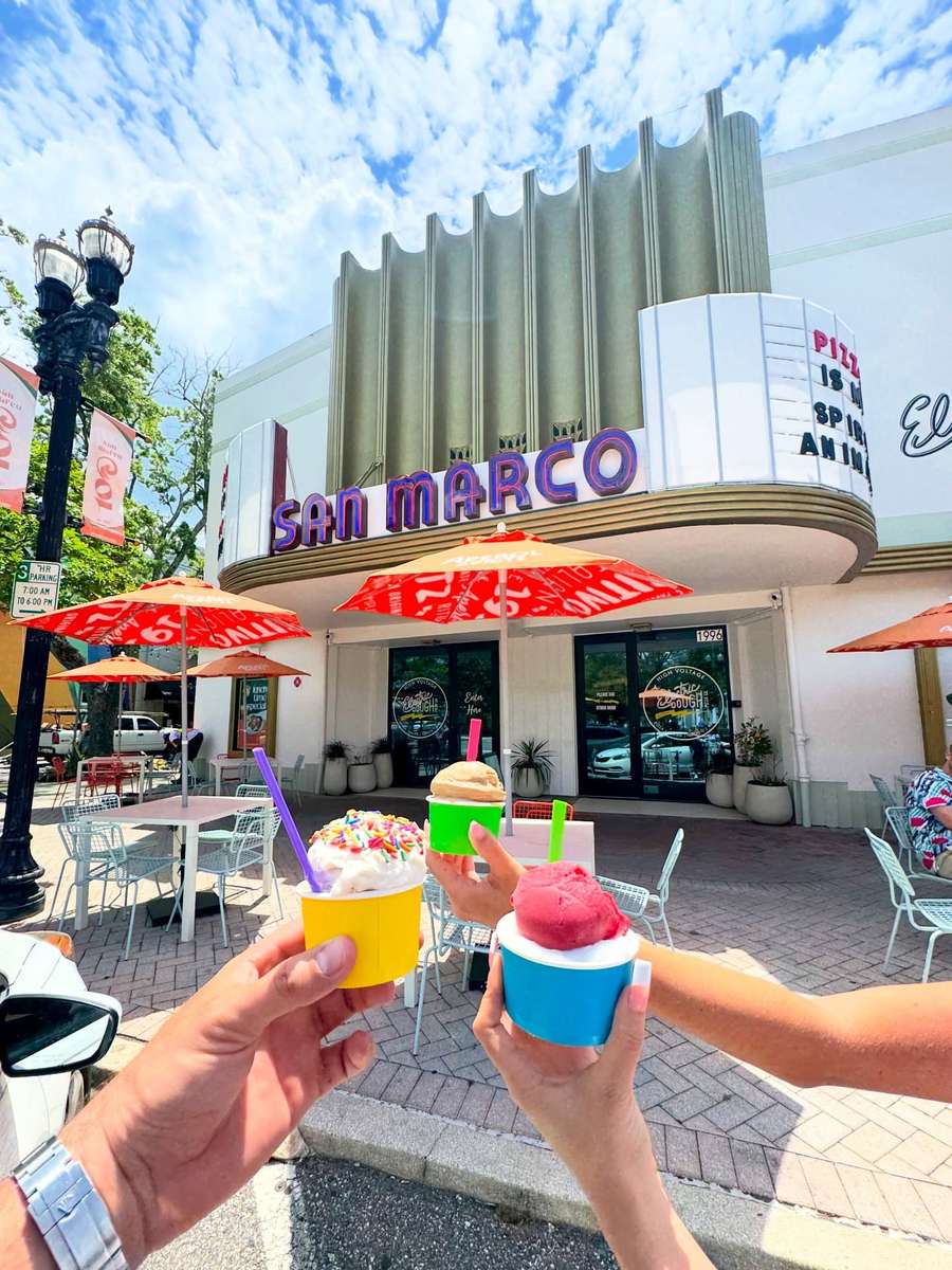 Two cups of Italian gelato held up in front of the San Marco marquee.