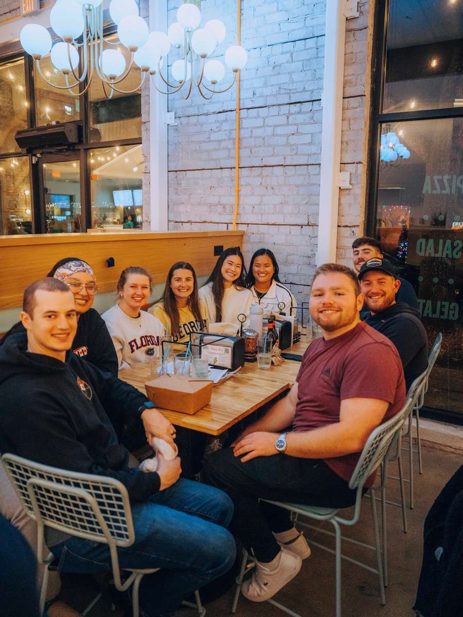 Friends around a table at Electric Dough Pizza Co. over pizza and drinks.