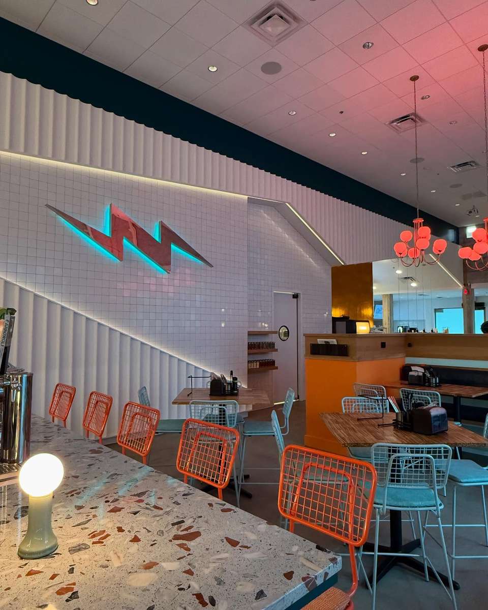The dining room at Electric Dough Pizza Co. in San Marco, Jacksonville, with the neon lightning bolt on the tile wall and the terrazzo counter.