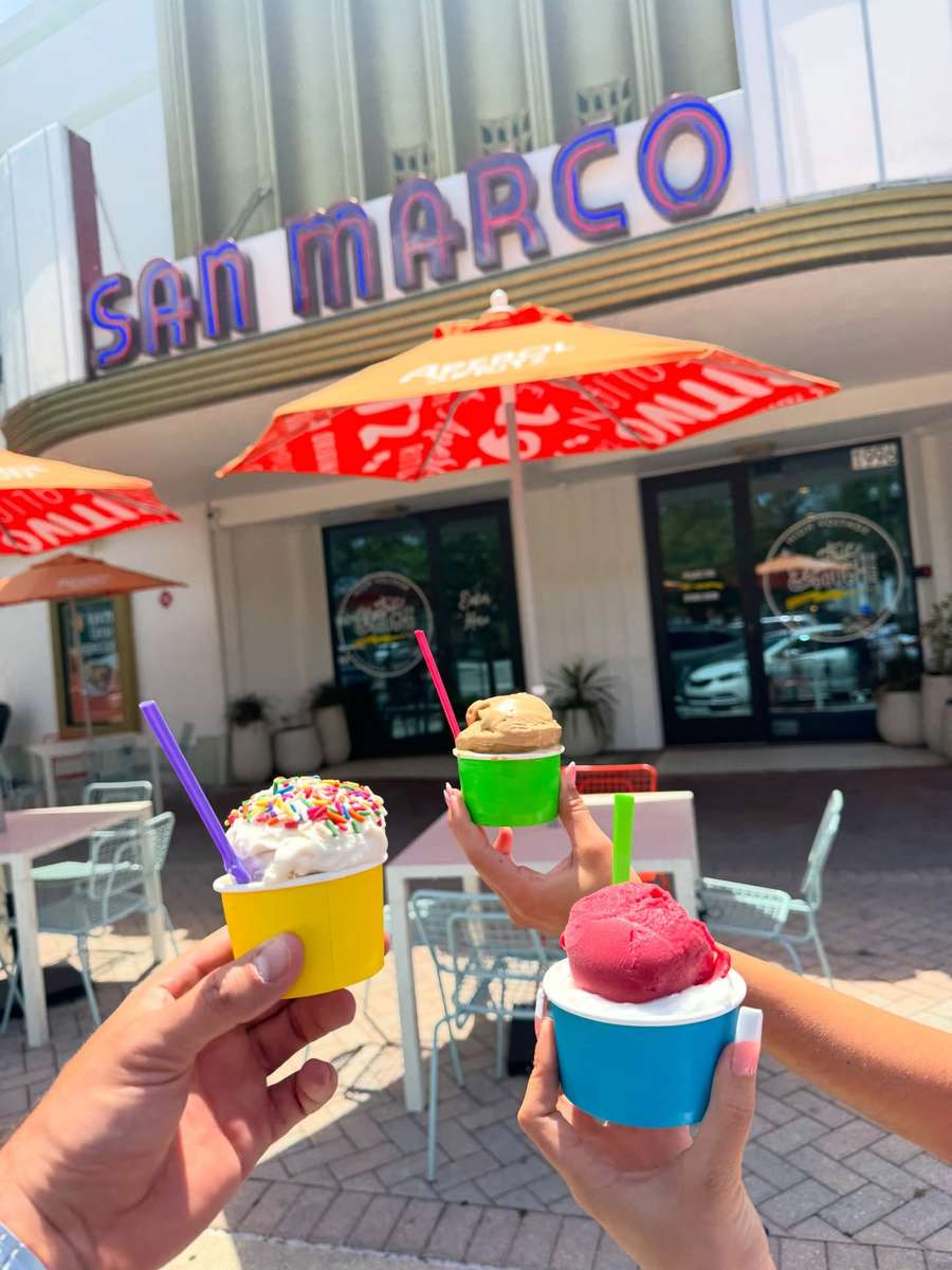 Three cups of Villa Dolce gelato and sorbetto held up under the San Marco Theatre marquee in Jacksonville, Florida.