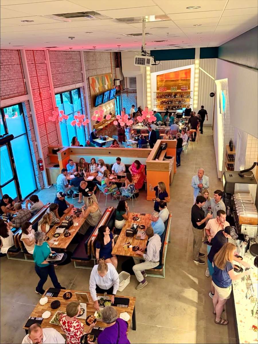 A packed dining room at Electric Dough Pizza Co., every table full under the marquee lights.