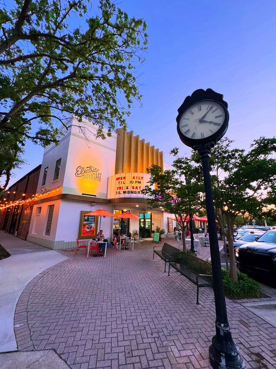 Dusk on San Marco Boulevard outside Electric Dough Pizza Co., the marquee reading open daily till 10pm and Friday and Saturday till midnight.