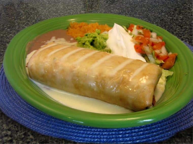 Burrito with melted cheese served with a side of guacamole, sour cream, pico de gallo and more sauces