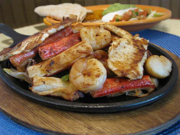 Seafood Fajitas with shrimp, Fish, scallops, onions, tomatoes, bell peppers, rice, beans and guacamole salad