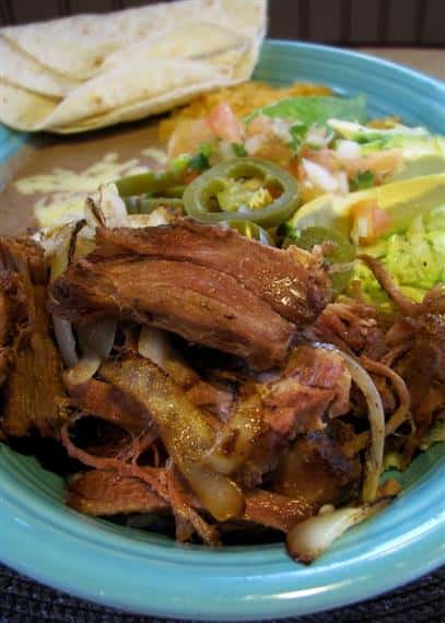 Pork dish served with grilled onions, shredded lettuce, tomato and tortilla chips