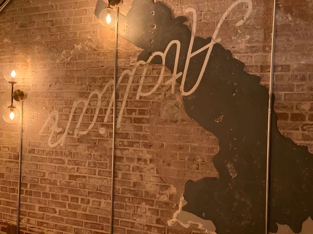 Brick wall with a stylized map outline and illuminated script sign reading "Good Spot."