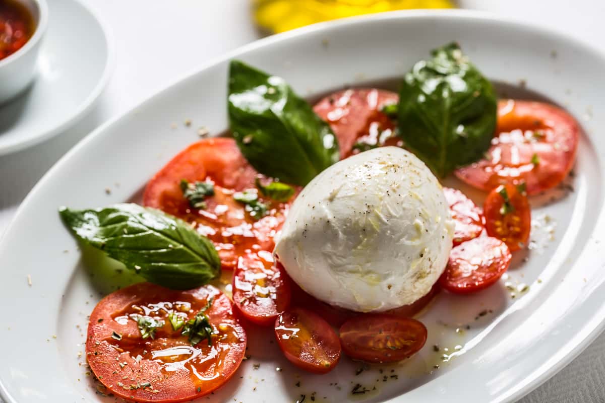 Caprese salad with sliced tomatoes, fresh mozzarella, basil, and olive oil.