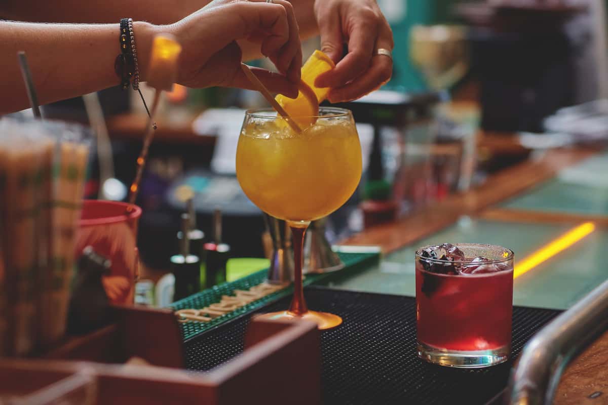 Bartender preparing a cocktail with fresh citrus garnish at a bar.