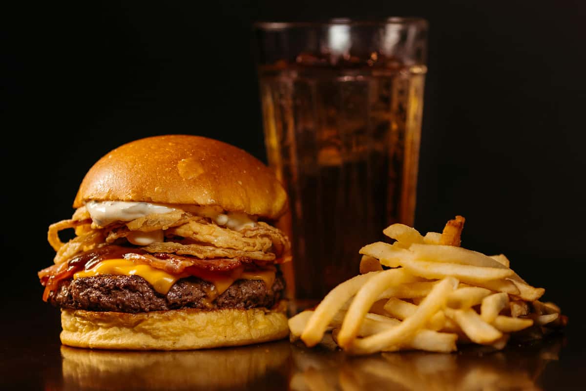 Savor a juicy cheeseburger with onion rings, fries, and a refreshing soft drink.