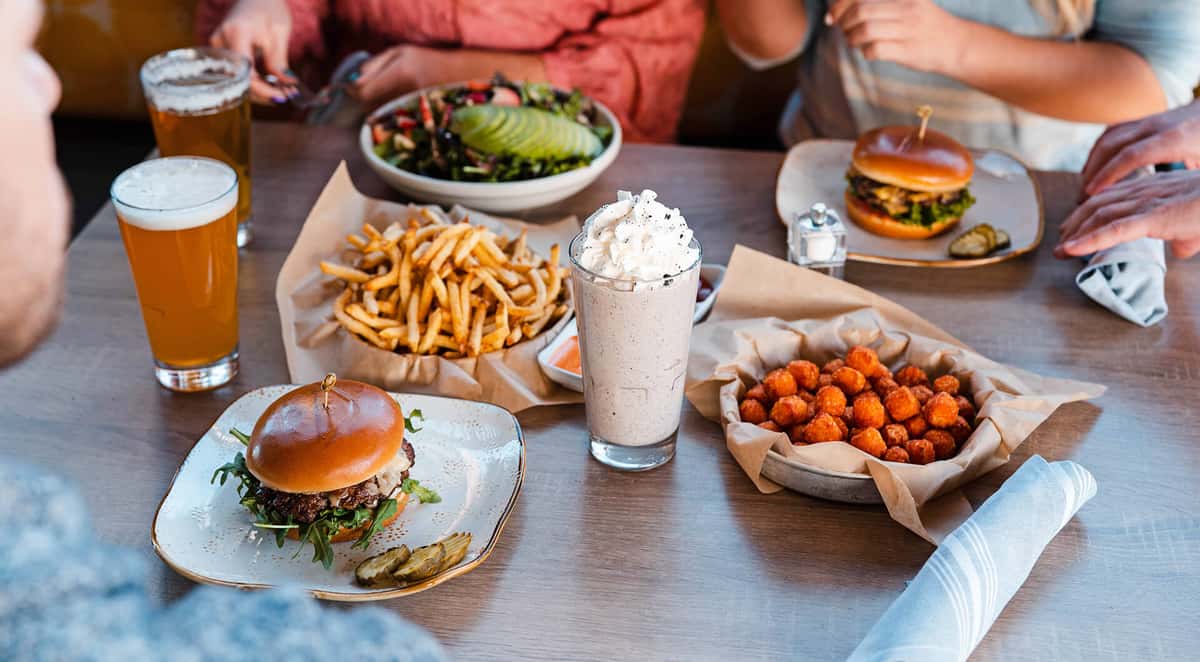 Overhead shot of Truland burger, tots, fries, salad, and shake