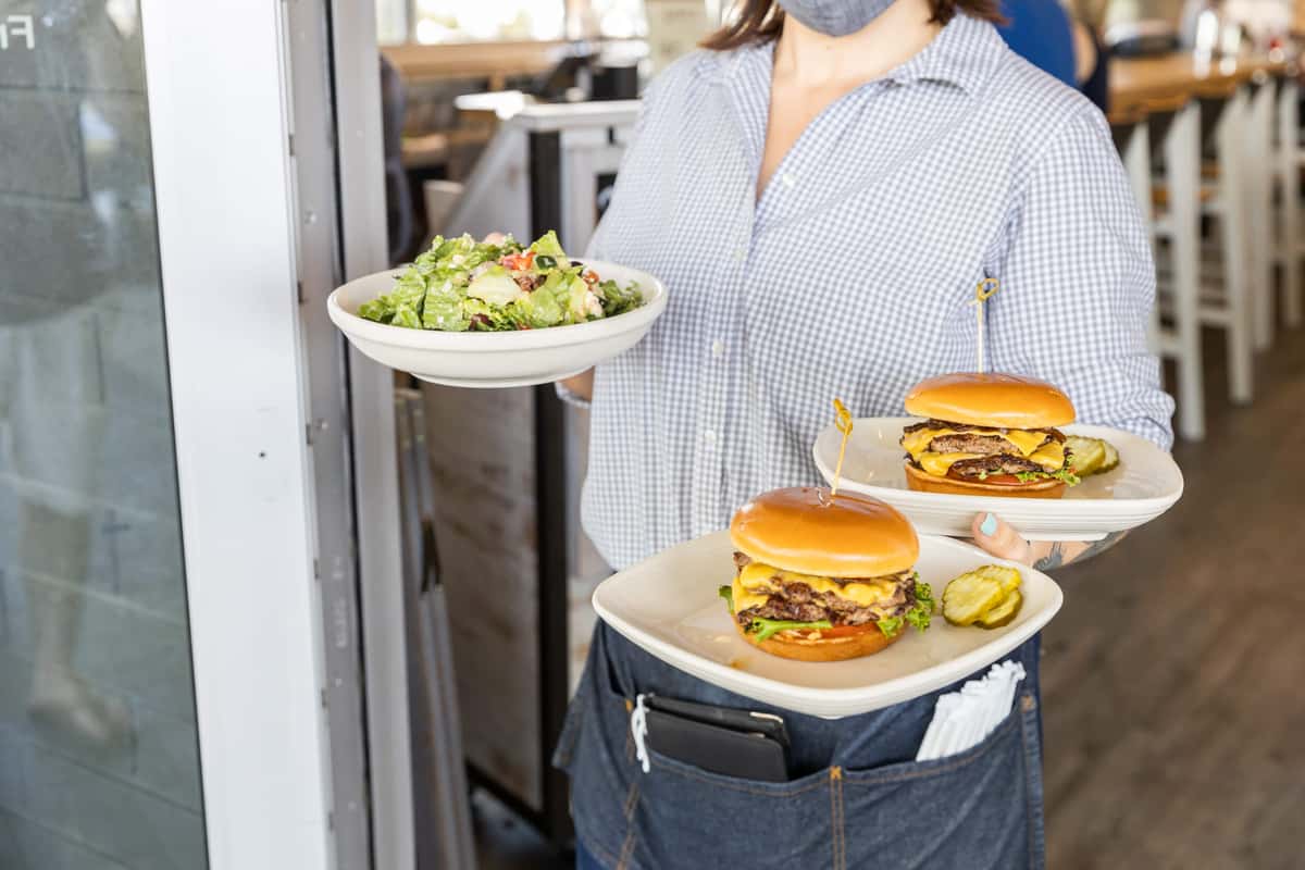 Waitress bringing out a salad and burgers