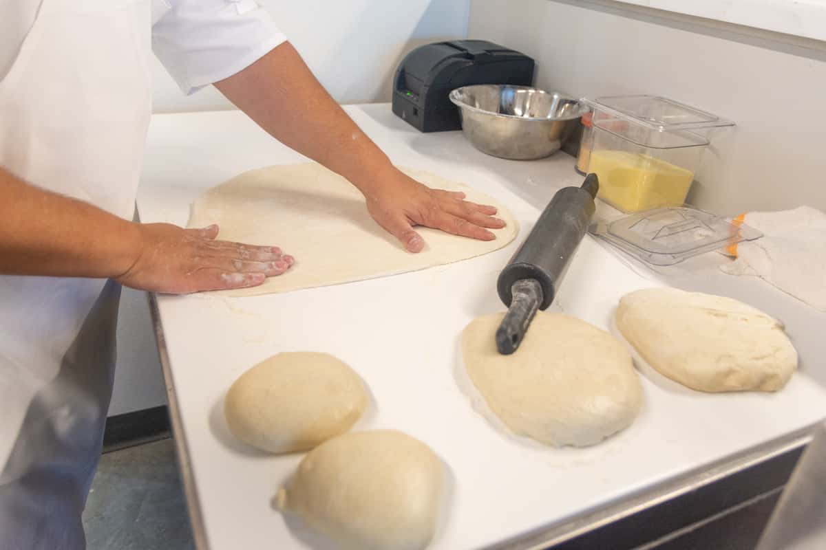 team member rolling pizza dough