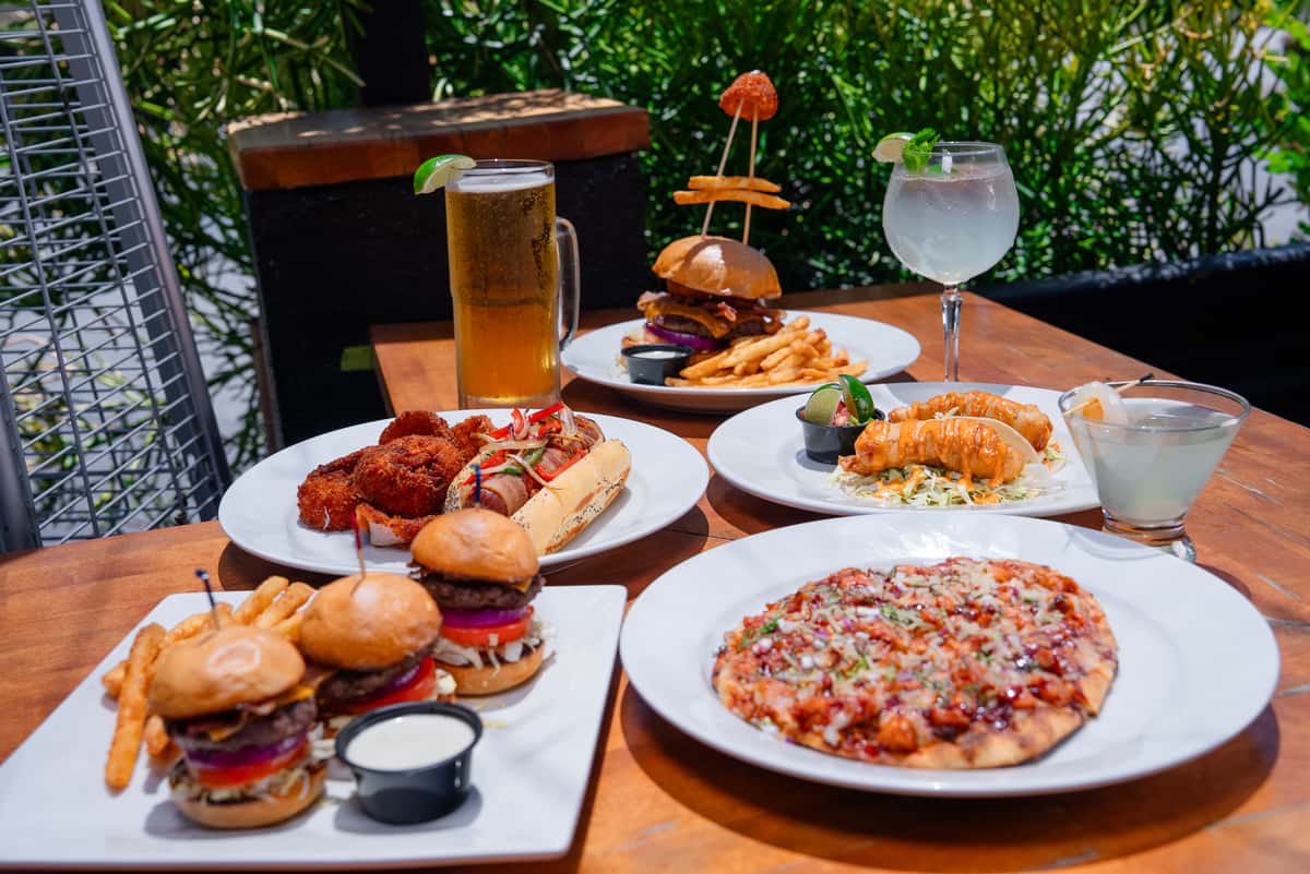 Landscape photo of the sliders, bbq chicken flatbread, fish tacos, Halo burger, and the hot dog with onion rings