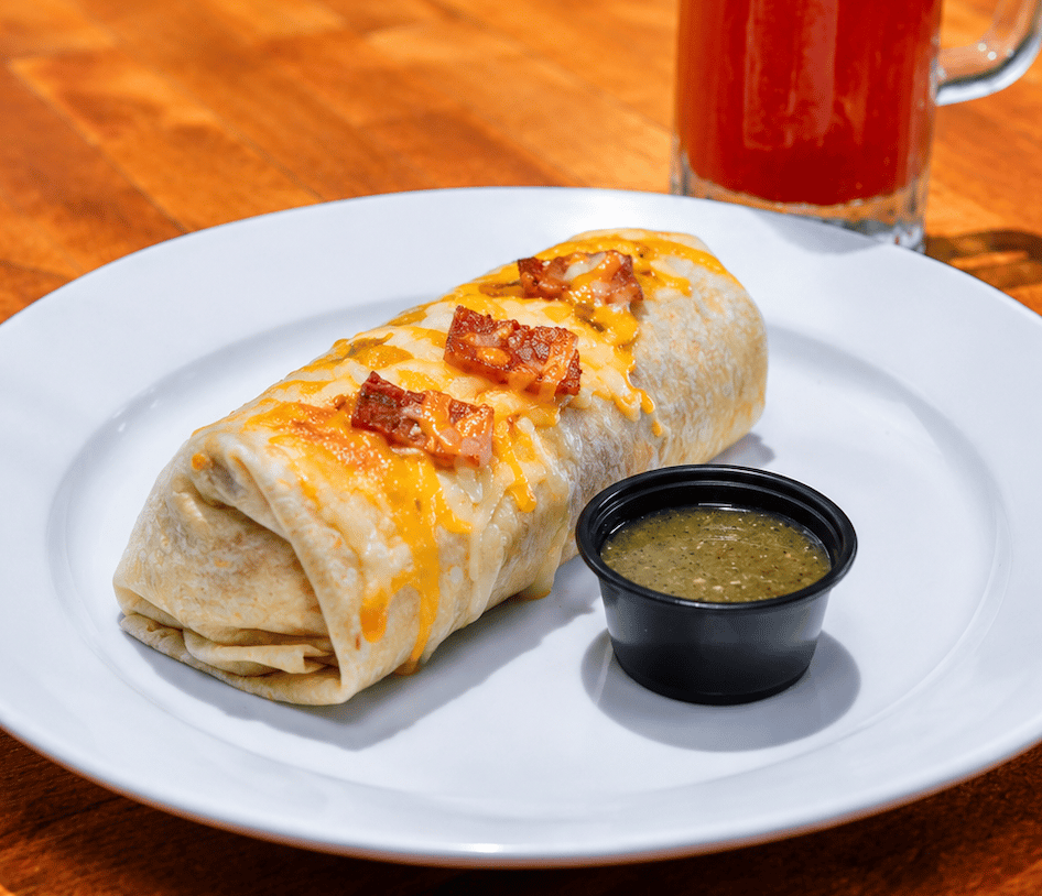 Breakfast burrito with scrambled eggs, melted cheese, ham, and green salsa