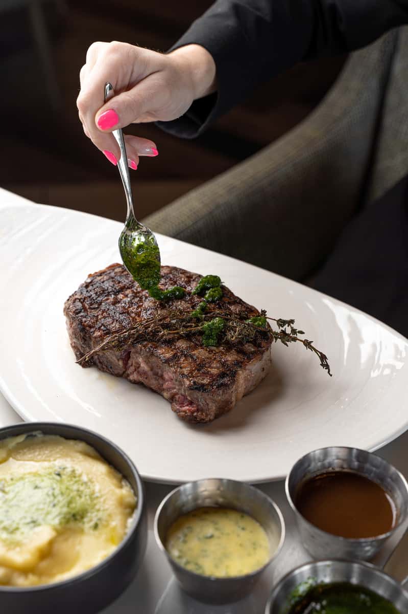Steak being drizzled with a sauce