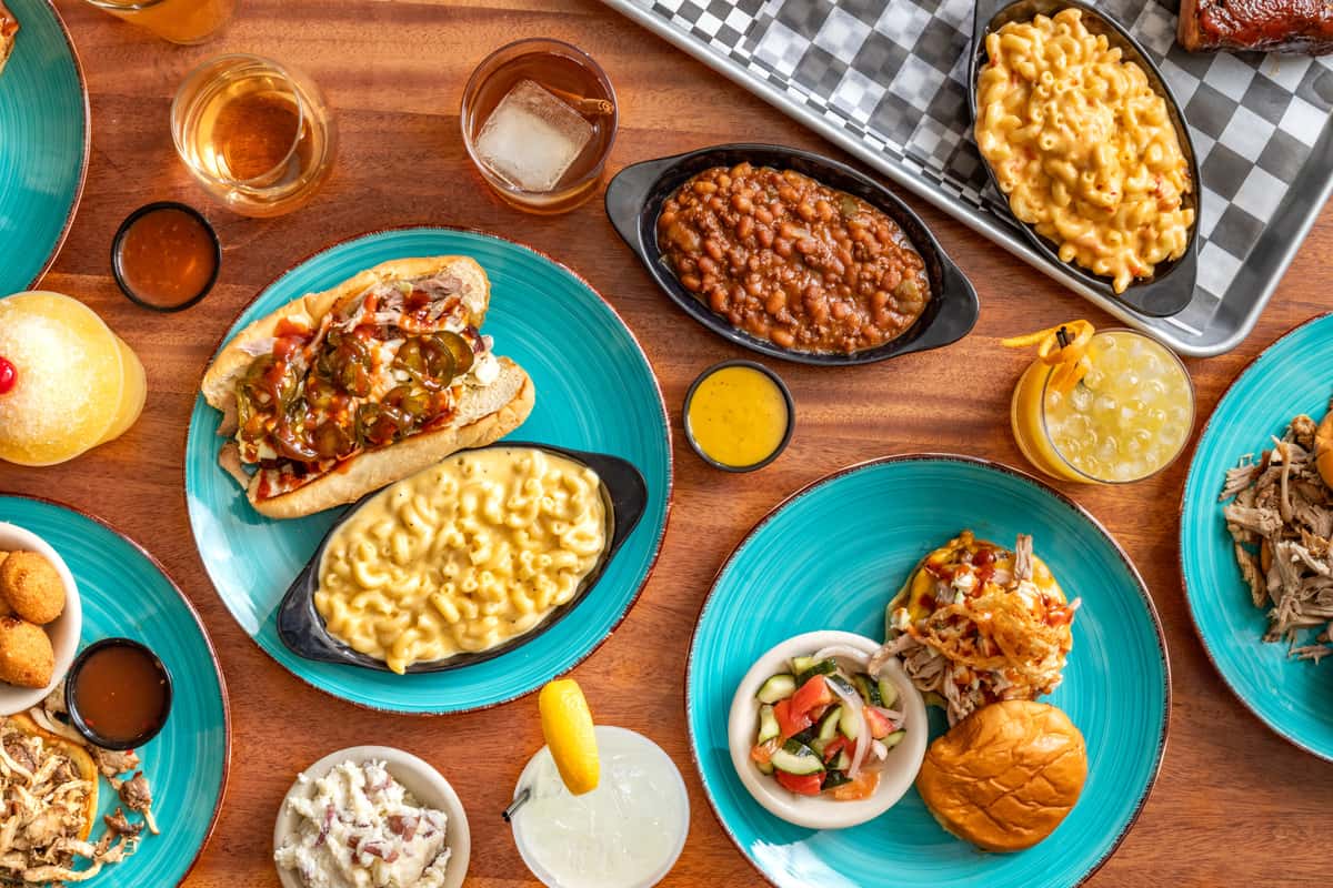 Group of dish including bbq, beans, chicken and dips