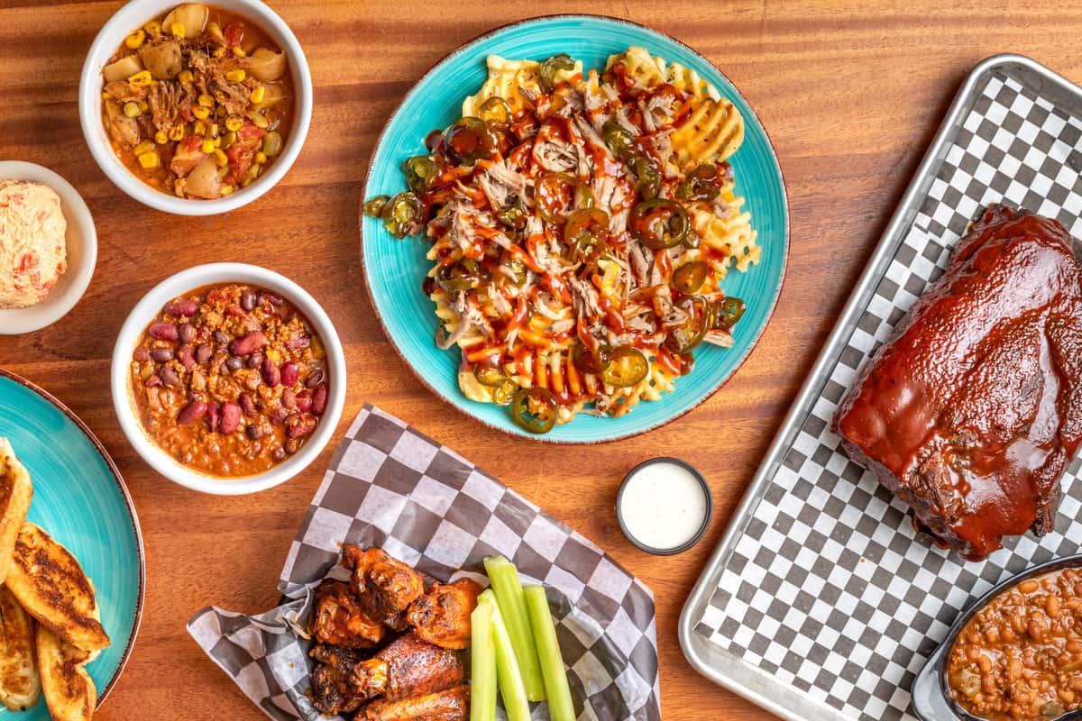 group of dishes including BBQ, beans, chicken and dips