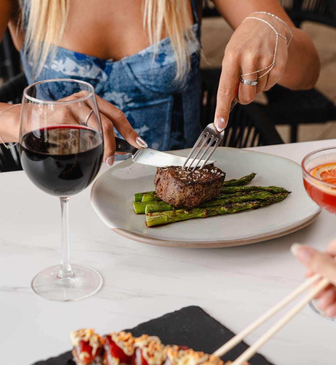 Cutting into Filet and asparagus with red wine glass